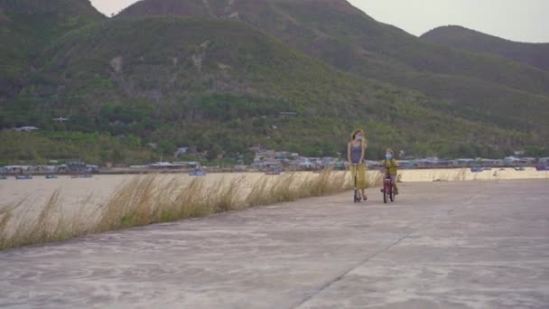 Menino da escola ativa e sua mãe andando de bicicleta e scooter com mochila no dia ensolarado. Criança feliz de bicicleta a caminho da escola. Maneira segura para crianças ao ar livre para a escola. As escolas estão abertas após o encerramento — Vídeo de Stock