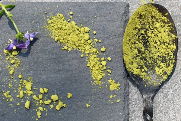 Bir kaşık kayrak renkli kutu üzerindeki yeşil Matcha tozu