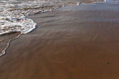 Basık bir dalga ile kumlu bir plaj bir arka plan