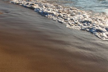 Basık bir dalga ile kumlu bir plaj bir arka plan