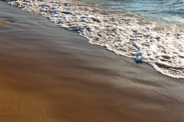 Basık bir dalga ile kumlu bir plaj bir arka plan