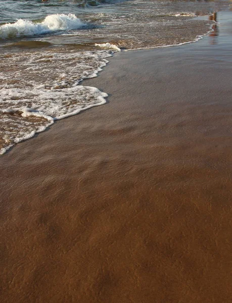 En bakgrund av en sandstrand med en vikande våg — Stockfoto