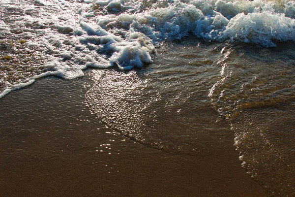 Un fondo de una playa de arena con una ola en retroceso — Foto de Stock