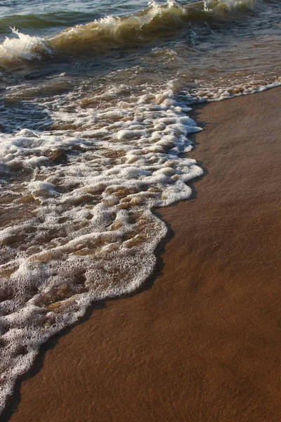 En bakgrund av en sandstrand med en vikande våg — Stockfoto