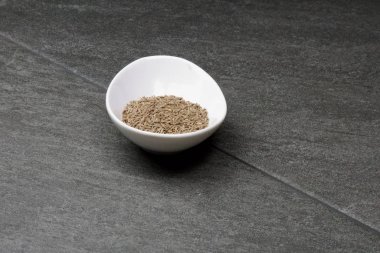 Gri arkaplandaki bir kasede fotokopi alanı olan kimyon tohumları.