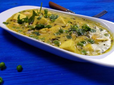 Krema soslu yeşil bezelyeli krema, nohut unu ve mavi ahşap arka planda Çemen yaprağı..