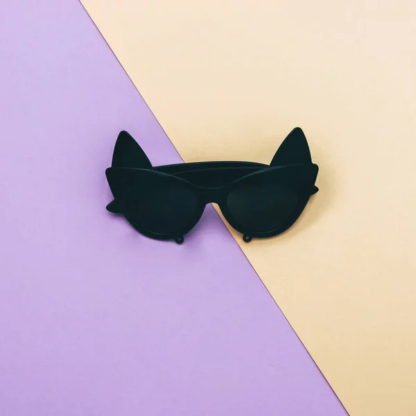 fashionable sunglasses shaped of cat eyes on yellow and purple background
