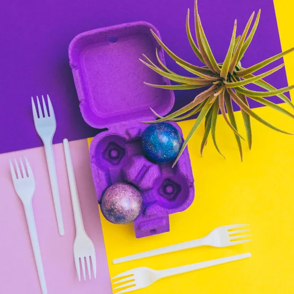 box with crazy magic dragon eggs with cosmic pattern on geometric background and plastic forks. art creative concept. minimal and surreal artwork