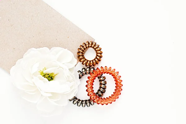 Conjunto plano de bandas espirales de cabello femenino y flor en un bac blanco — Foto de Stock