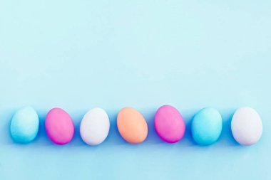 Satır mavi arka plan üzerinde renkli Paskalya yortusu yumurta 