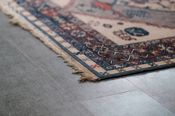 Ornamental design carpet on grey tile floor — Stock Photo, Image