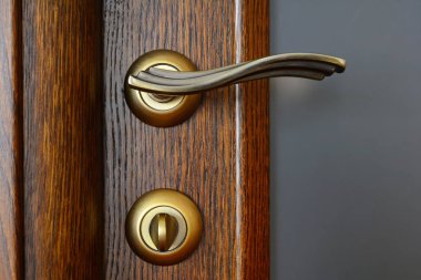 Vintage brass door handle with a latch and a lock on the wooden  clipart