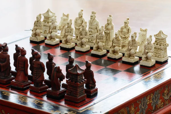 Carved chess pieces in chinese style on a chessboard.