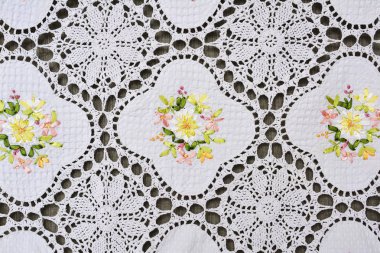 Çok renkli süslü çiçek desenli beyaz pamuklu dantel tablecl üzerinde