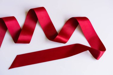 Parlak dekoratif kırmızı saten kurdele beyaz arka plan üzerinde. Scarlet t