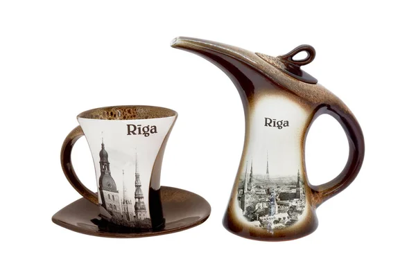 Керамический чайник и чашка и блюдце для кофе или чая. Сувенирные блюда с изображением города Риги. Изолированный, белый фон . — стоковое фото