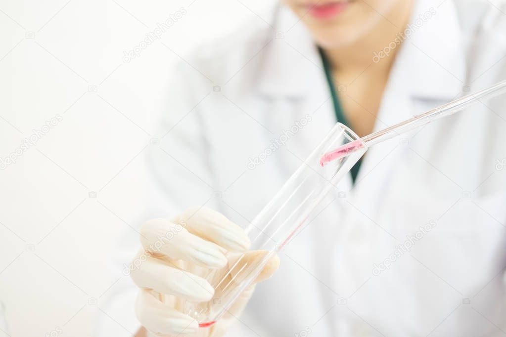Young Asian scientist working in the lavatory with test tubes and other equipment to discover new drugs
