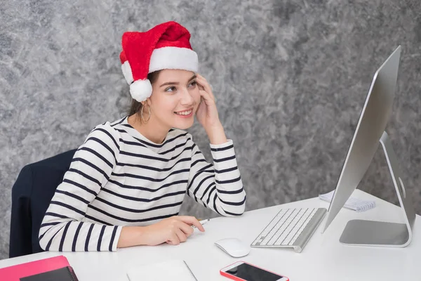 Güzel genç kız ofiste bir Noel Baba Noel şapka — Stok fotoğraf