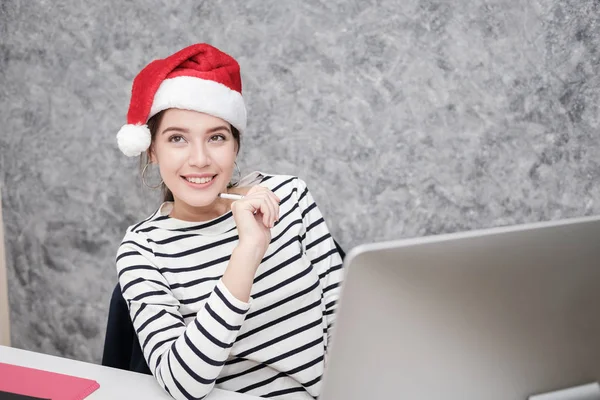 Krásná mladá dívka, která nosí santa vánoční čepice v kanceláři — Stock fotografie