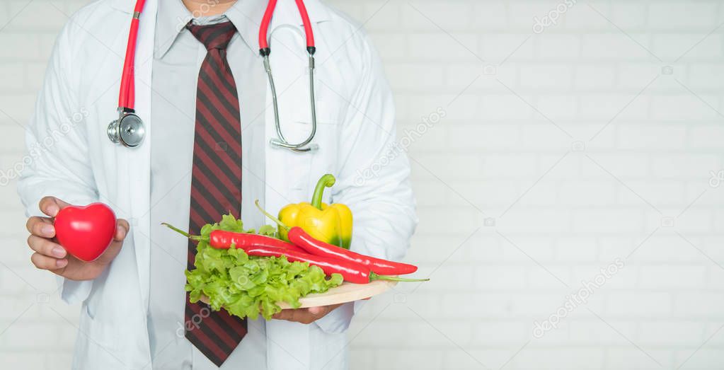 A health professional or doctor holding a tray of healthy fruit and vegetables to promote eating healthy to prevent disease