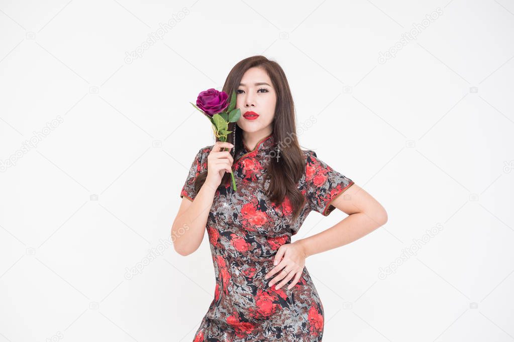 Beautiful young fashionable Asian woman holding flowers against a plain background