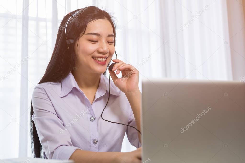 Young beautiful girl working at a laptop in a small medium enterprise. She is operating the phones and computer