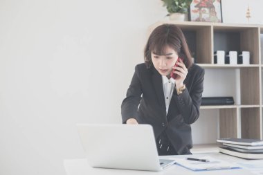 Genç ve güzel Asyalı bir kadın bir müşterisiyle telefonda konuşuyor. 