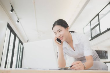 İş yerinde gülümseyen genç bir iş kadınının portresi, küçük bir paketin maliyetini hesaplamak, online alışveriş için küçük işletme kaygıları. 