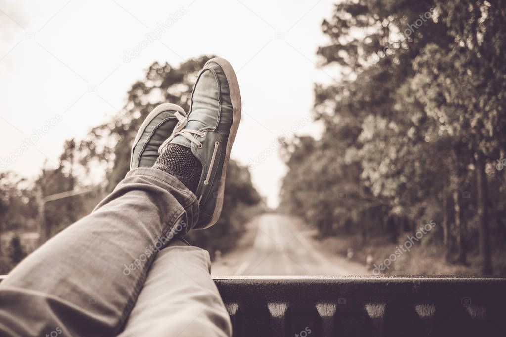 young asian man sit in a truck and looking at his feet and beautiful road