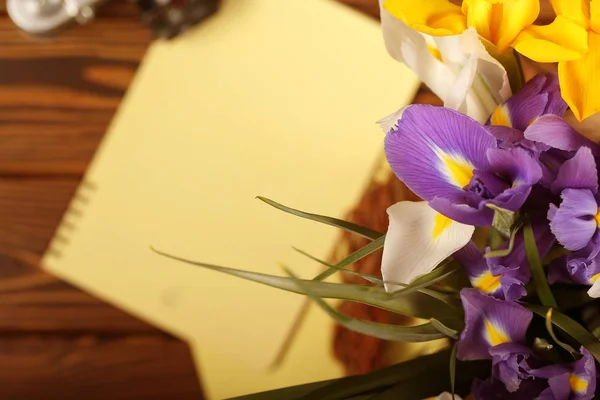 notebook, camera and flowers are on the table