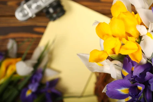 notebook, camera and flowers are on the table