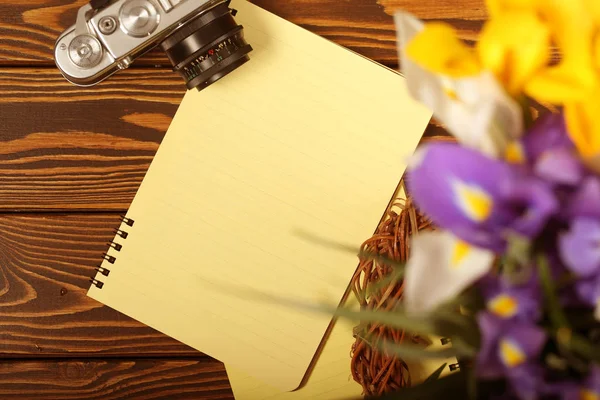notebook, camera and flowers are on the table