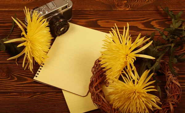 notebook, camera and flowers are on the table