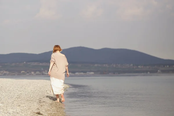 a girl walks on the sea barefoot on a Sunny spring day