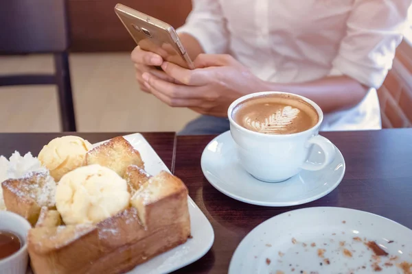 Las mujeres de Asia que beben café y miran su teléfono celular en la sa — Foto de Stock