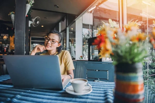 快乐的亚洲女人坐在咖啡店里用笔记本电脑 — 图库照片