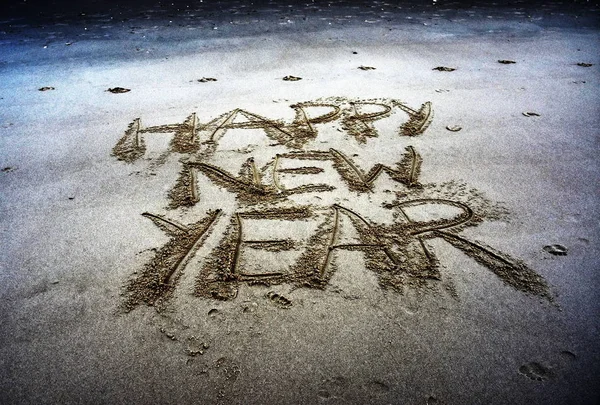 Happy new year written on sand at sunset. — Stock Photo, Image