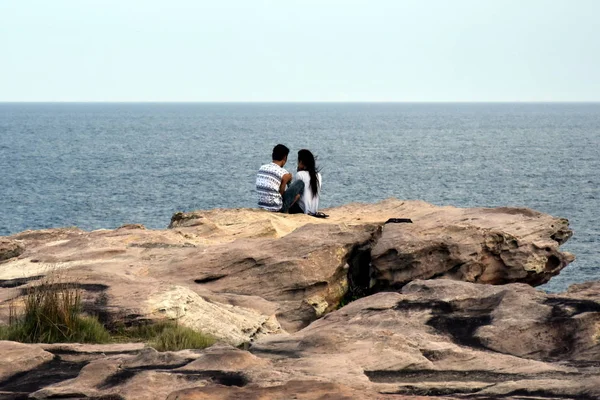 Young asian couple sitting on the rock — Stock Photo, Image