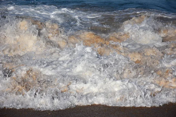 Water foam of the waves crushing into the shore — Stock Photo, Image