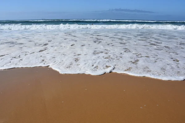 Fala i piaszczysta plaża na tle — Zdjęcie stockowe