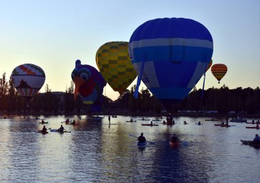 Canberra, Avustralya - 11 Mart 2018. Büyük renkli sıcak hava balonları, göl Burley Griffin, balon muhteşem festivalin bir parçası olarak izlerken kanocu.