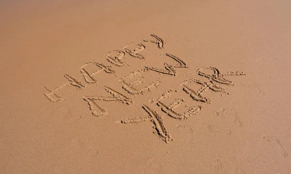 Happy new year written on sand at sunset. Happy New Year lettering on the beach. 