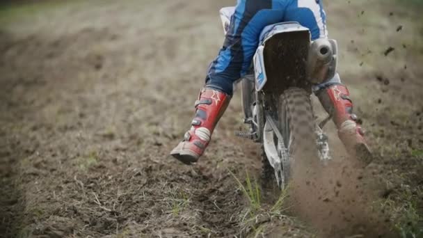 Мотокрос гонщик починає їздити на своїй брудній гонці Cross MX велосипед, що піднімає пил заднього виду, повільний рух — стокове відео