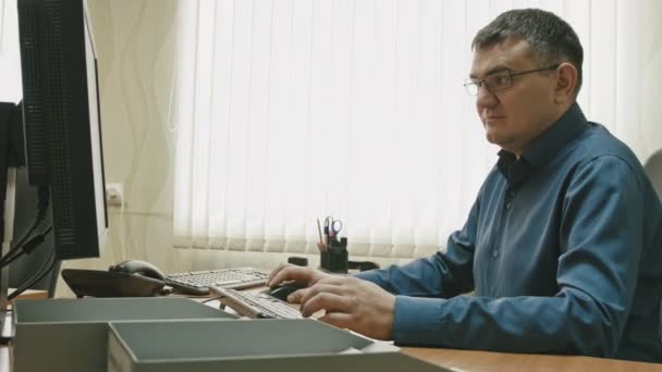 Trabajador de oficina en gafas delante de la computadora de escritorio, toma de diapositivas — Vídeos de Stock