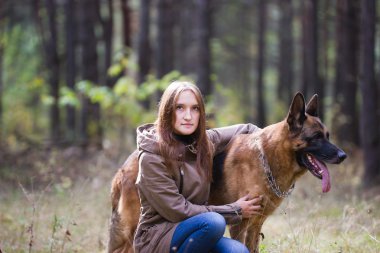 Young attractive woman posing with German Shepherd dog outdoors in the autumn park, close up