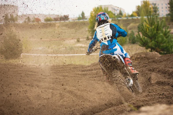 Moto cross - MX chica motorista en la carrera en Rusia - un giro brusco y el spray de suciedad, vista trasera —  Fotos de Stock