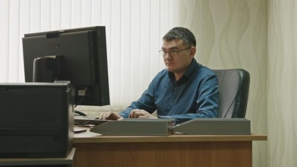 Stuff in office: working man in glasses working at computer, wide angle — Stock Video