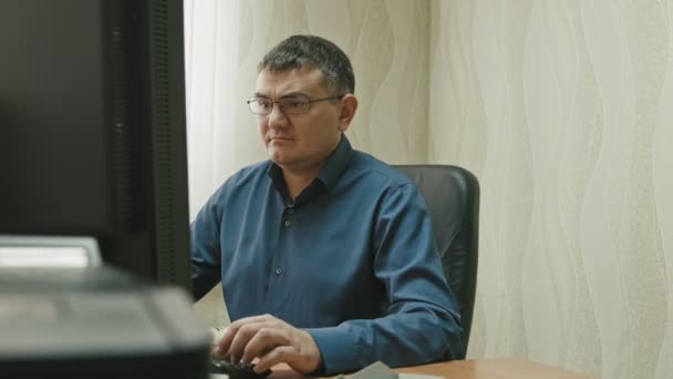 Stuff in office: man in glasses working at computer, use keyboard and mouse — Stock Video