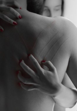 Womans hand scratching down mans bare back - black and red
