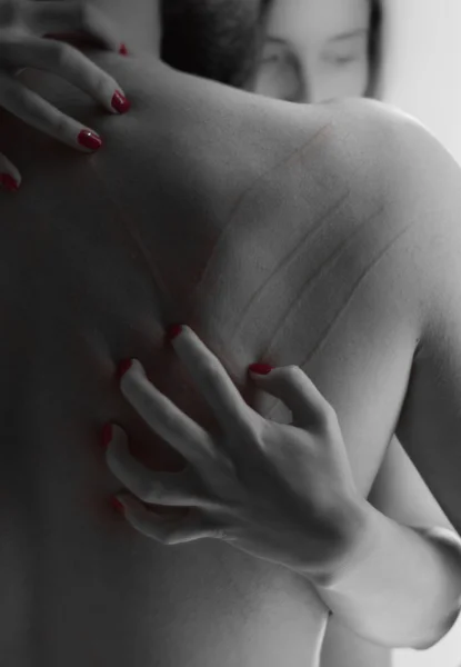 Womans hand scratching down mans bare back - black and red